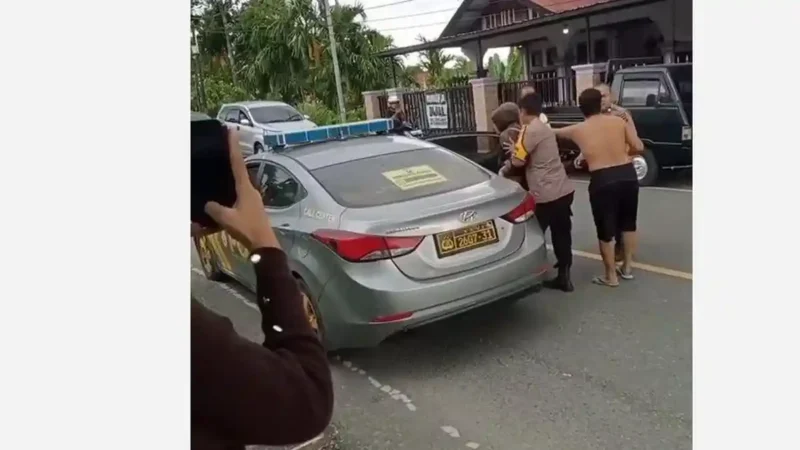 Seorang pria di Kerinci dimasukkan ke mobil sedang patroli polisi, Rabu (10/6/2026). Peristiwa itu terjadi di Kecamatan Tanah Kampung, Kota Sunfgai Penuh, saat siang hari.( poto : tribunjambi.com )