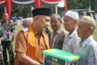 Bupati Bungo menyerahkan paket sembako kepada warga kurang mampu usai pembukaan TMMD Ke-129 di Desa Tanjung Agung. (poto: jambiprima.com).
