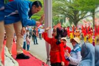 Bupati Merangin H M Syukur menyapa sepasang pengantin cilik di Pawai Akbar Pelajar memeriahkan Hari Ulang Tahun (HUT) ke-81 Republik Indonesia.(poto: meranginkab.go.id).