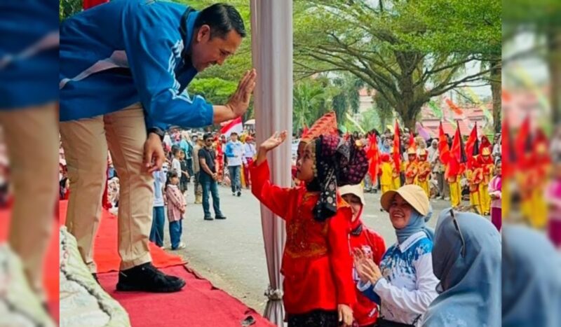 Bupati Merangin H M Syukur menyapa sepasang pengantin cilik di Pawai Akbar Pelajar memeriahkan Hari Ulang Tahun (HUT) ke-81 Republik Indonesia.(poto: meranginkab.go.id).
