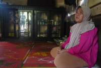 Tita, ibu rumah tangga warga tranmigran di Sungai Bermas, Kerinci, Jambi, duduk di rumahnya. Kini, ia masih menanti hak lahan usaha II, janji dari program transmigrasi.(poto: istimewa).