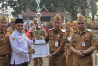 Sekda Alpian menyerahkan piala penghargaan Lomba Barisan Indah kepada Kepala Sekolah MTsn 1 Sungai Penuh,Bapak Soni Indra.(poto: istimewa).