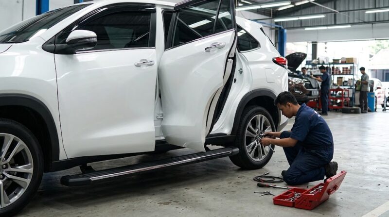 Mekanik memasang footstep elektrik pada bodi mobil Toyota Innova Zenix untuk memudahkan akses keluar-masuk penumpang.(poto: AI).
