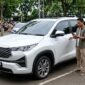 Ilustrasi Pengemudi mencoba fitur T Intouch with Toyota Remote pada Kijang Innova Zenix terbaru di area parkir.(poto: AI).