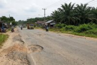 Ilustrasi: Kondisi jalan rusak penuh lubang di kawasan Sengeti, Muaro Jambi, yang kini siap diperbaiki melalui proyek preservasi.(poto: AI).
