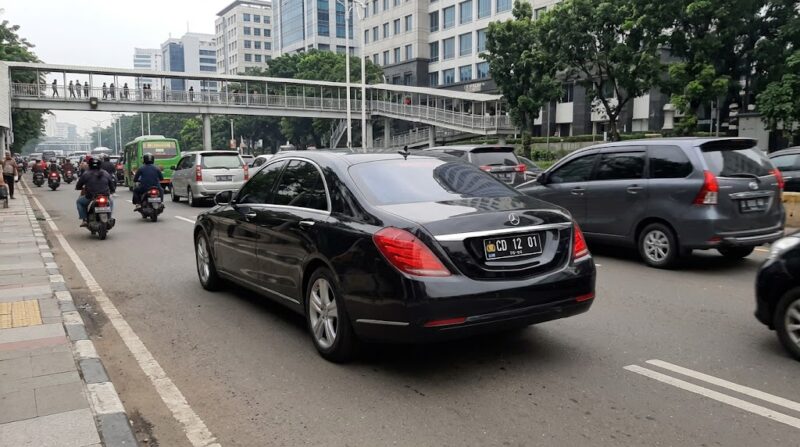 Mobil dinas korps diplomatik dengan plat nomor khusus CD 12 01 melintas di tengah arus lalu lintas perkotaan Indonesia. (ilustrasi poto: AI).