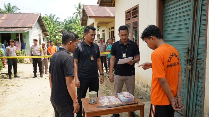 Ilustrasi: Pelaku pencurian di Sarolangun (baju oranye) menunjukkan barang bukti emas dan uang saat pemeriksaan oleh polisi.(poto: AI).