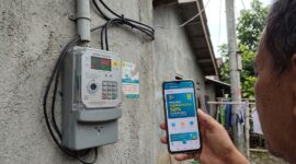 Warga mengecek promo tambah daya 50 persen di PLN Mobile dekat meteran listrik rumah.(ilustrasi poto: AI).