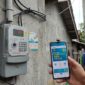 Warga mengecek promo tambah daya 50 persen di PLN Mobile dekat meteran listrik rumah.(ilustrasi poto: AI).