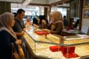 Pelayan toko emas di Jambi menunjukkan kalung perhiasan kepada pembeli di depan etalase berkilau penuh perhiasan.(poto: jemarionline.com).