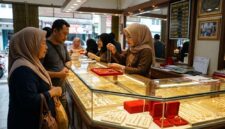 Pelayan toko emas di Jambi menunjukkan kalung perhiasan kepada pembeli di depan etalase berkilau penuh perhiasan.(poto: jemarionline.com).