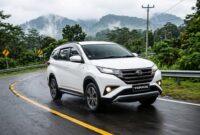 Ilustrasi Daihatsu Terios putih melaju mulus melintasi jalanan aspal berkelok di kawasan perbukitan yang hijau dan berkabut tebal.(poto: AI).