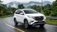 Ilustrasi Daihatsu Terios putih melaju mulus melintasi jalanan aspal berkelok di kawasan perbukitan yang hijau dan berkabut tebal.(poto: AI).