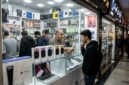 Ilustarsi Seorang pemuda melihat kotak iPhone 18 yang dipajang di etalase toko elektronik Charsou Mall, Teheran.(poto: AI).