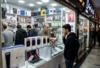 Ilustarsi Seorang pemuda melihat kotak iPhone 18 yang dipajang di etalase toko elektronik Charsou Mall, Teheran.(poto: AI).
