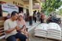 Ilustrasi Warga memeriksa status penerimaan bansos beras 30 kg lewat ponsel pakai NIK KTP di balai desa.(poto: AI).