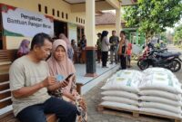 Ilustrasi Warga memeriksa status penerimaan bansos beras 30 kg lewat ponsel pakai NIK KTP di balai desa.(poto: AI).