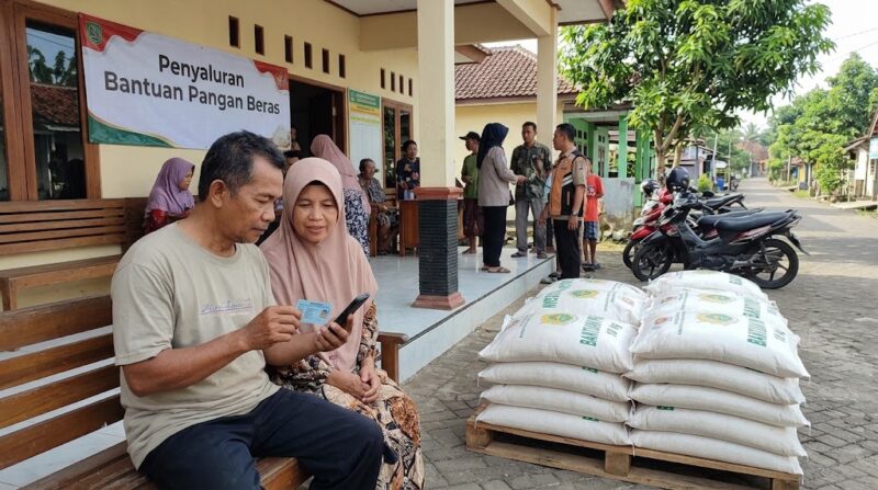 Ilustrasi Warga memeriksa status penerimaan bansos beras 30 kg lewat ponsel pakai NIK KTP di balai desa.(poto: AI).