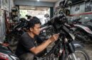 Ilustrasi: Mekanik sedang memasang sistem kunci keyless pada motor bebek di sebuah bengkel modifikasi di Jakarta.(poto: AI).