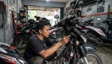 Ilustrasi: Mekanik sedang memasang sistem kunci keyless pada motor bebek di sebuah bengkel modifikasi di Jakarta.(poto: AI).