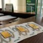 Emas batangan Antam tersusun di meja kasir Pegadaian, siap ditransaksikan nasabah dengan harga jual dan buyback baru.(poto: AI).