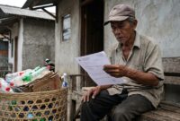 Ilustrasi: Seorang lansia pemulung memeriksa surat data kependudukan di teras rumahnya terkait sengkarut verifikasi bantuan sosial.(poto: AI).